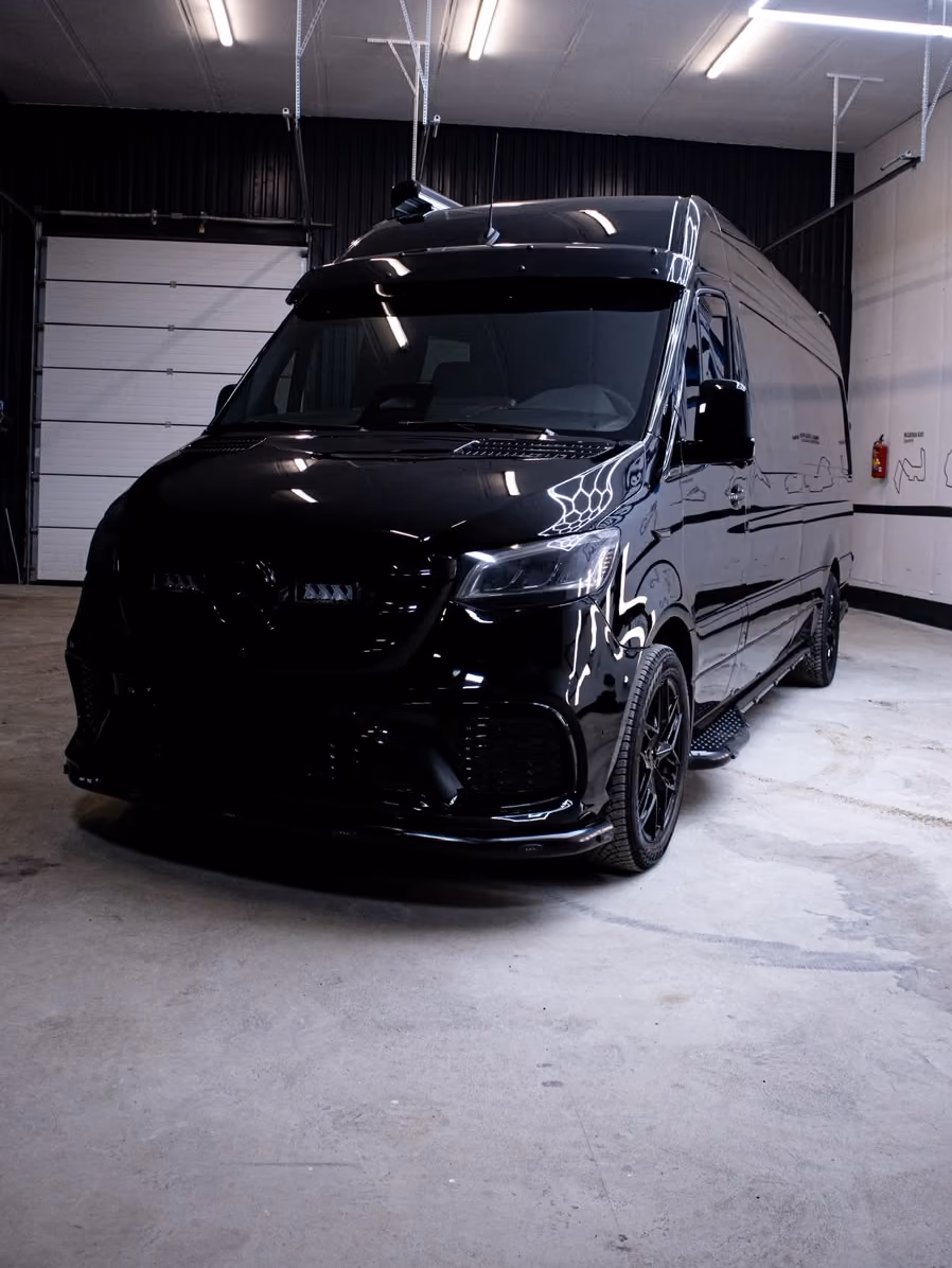 Musta Mercedes-Benz Sprinter KM-Detailingin hallissa kuusikulmiovalojen alla