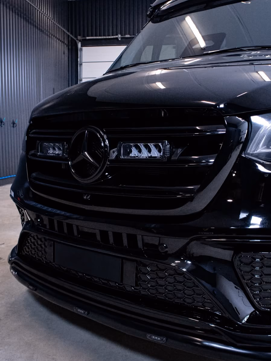 Mustan Mercedes-Benz Sprinterin kiiltävä keula ja LED-lisävalot