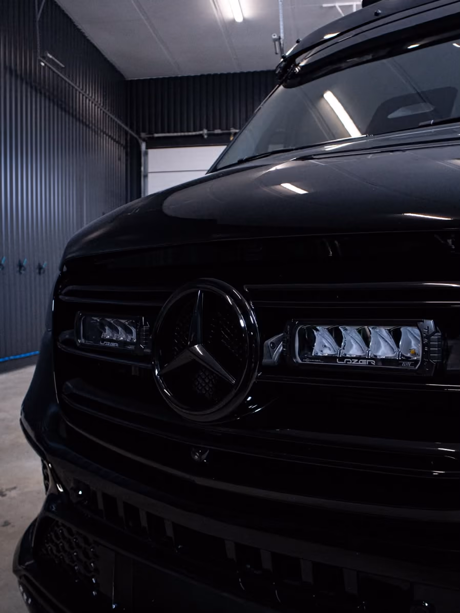 Mustan Mercedes-Benz Sprinterin maski ja lisävalot lähikuvassa