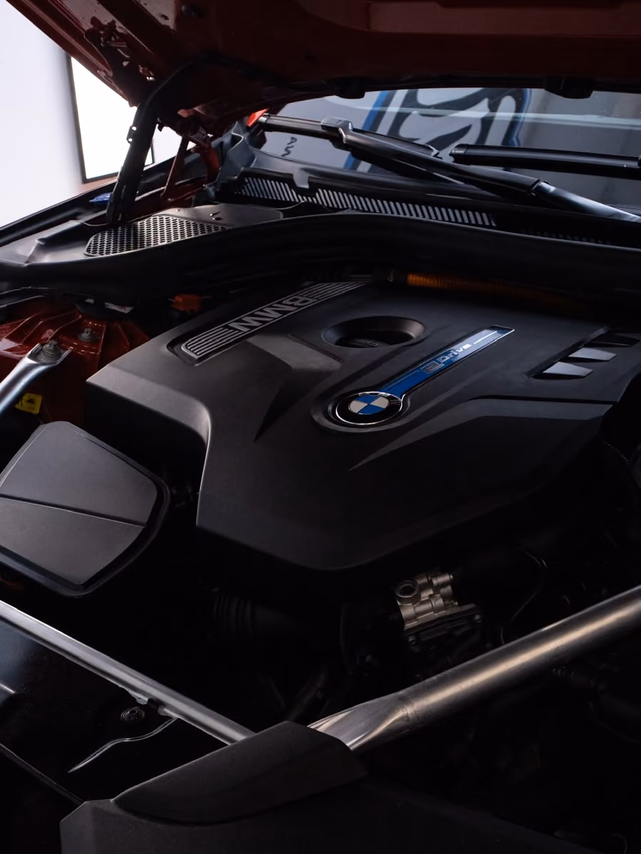 Pesty BMW:n moottoritila: puhdas moottorin suojakansi ja käsitellyt muovipinnat