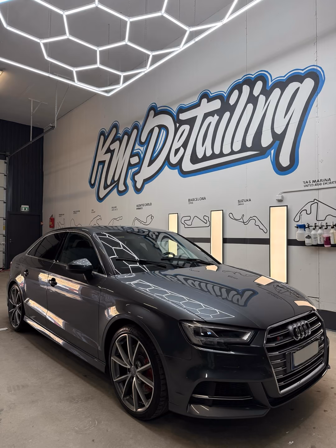 Harmaa Audi S3 Sedan pinnoituksen jälkeen KM-Detailingin hallissa: konepellistä heijastuvat logo ja kuusikulmiovalot