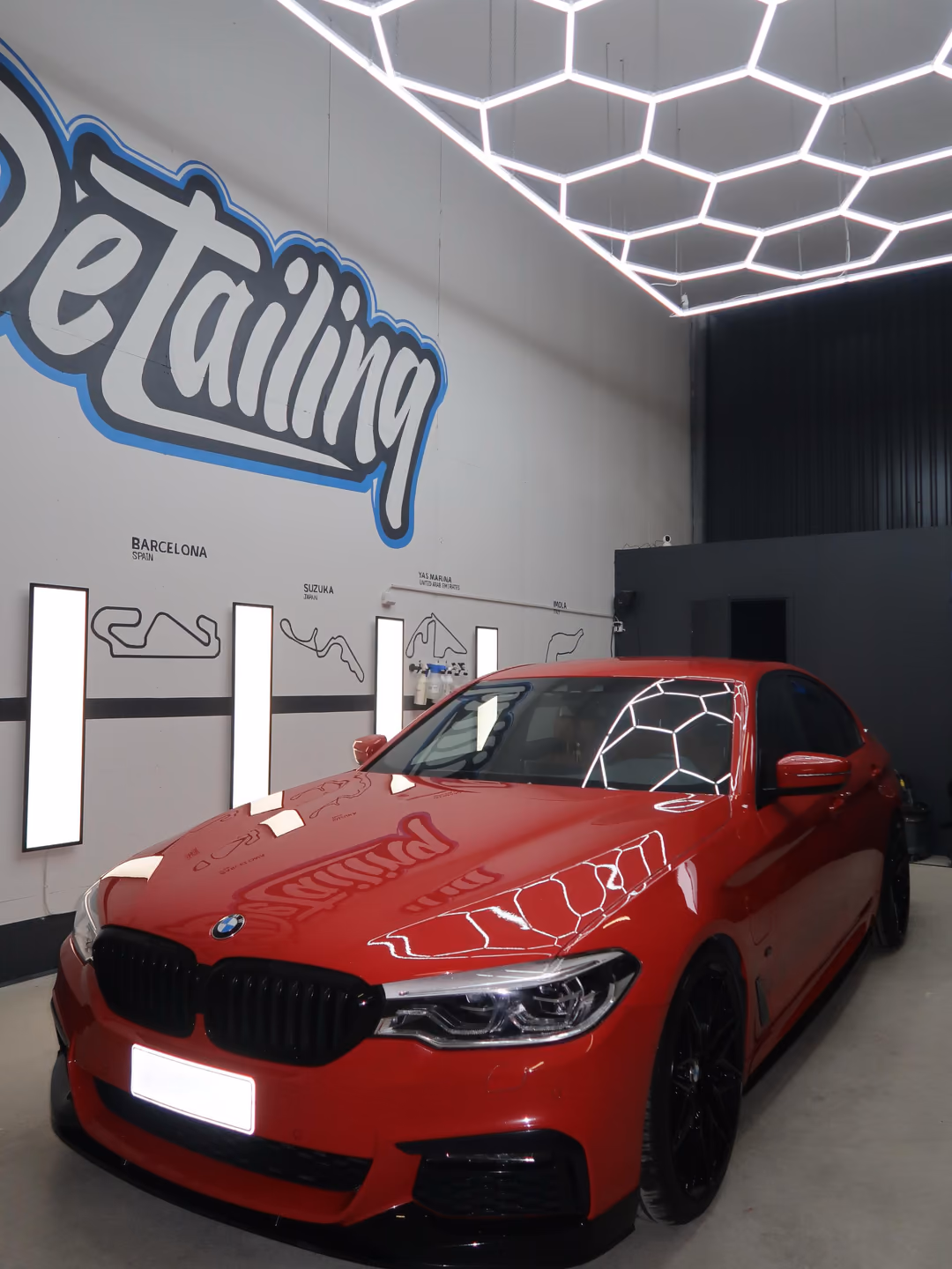 Punainen BMW 5-sarja pinnoituksen jälkeen KM-Detailingin hallissa kuusikulmiovalojen alla