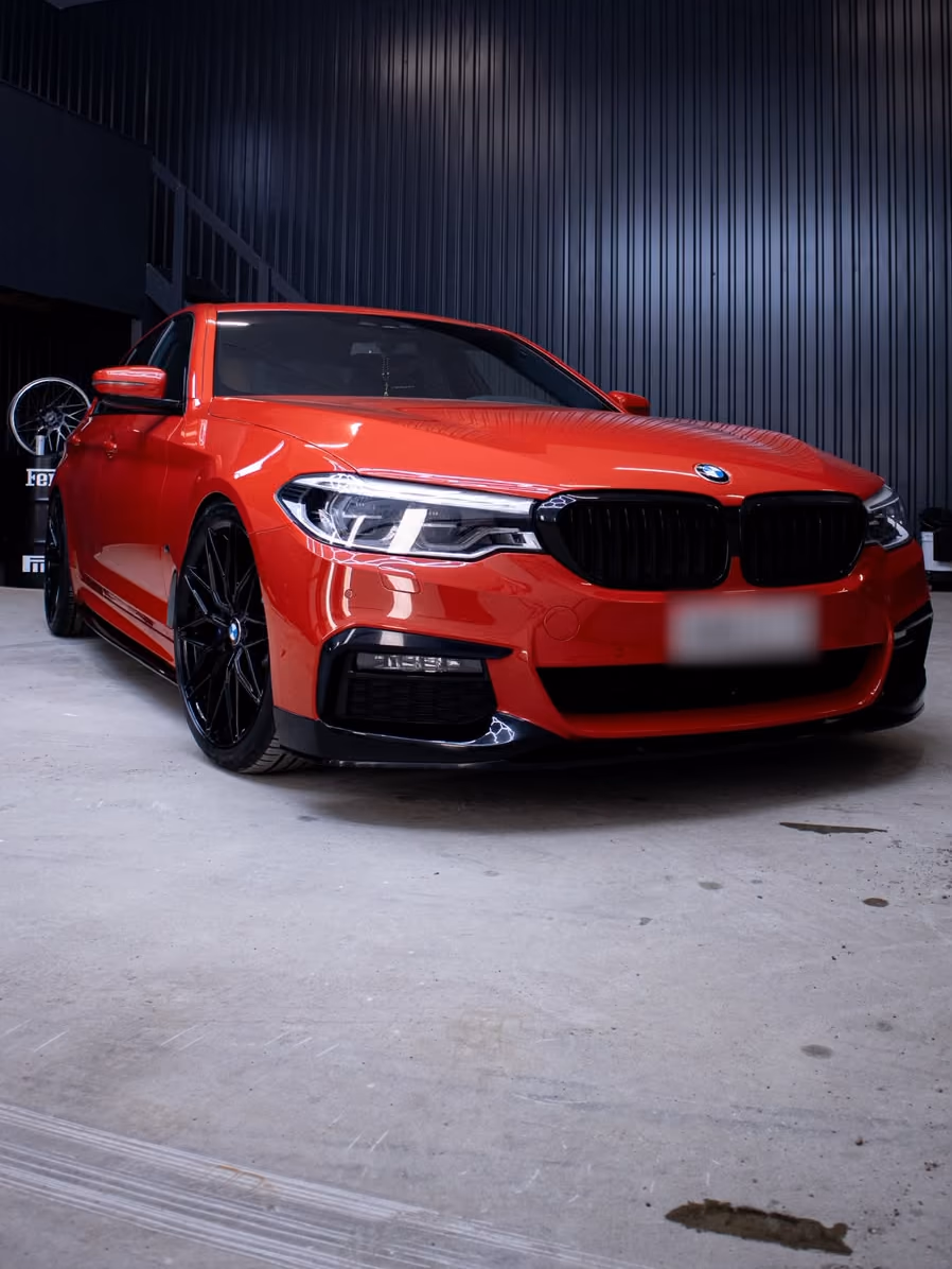 Punainen BMW 5-sarja edestä KM-Detailingin hallissa käsittelyn jälkeen