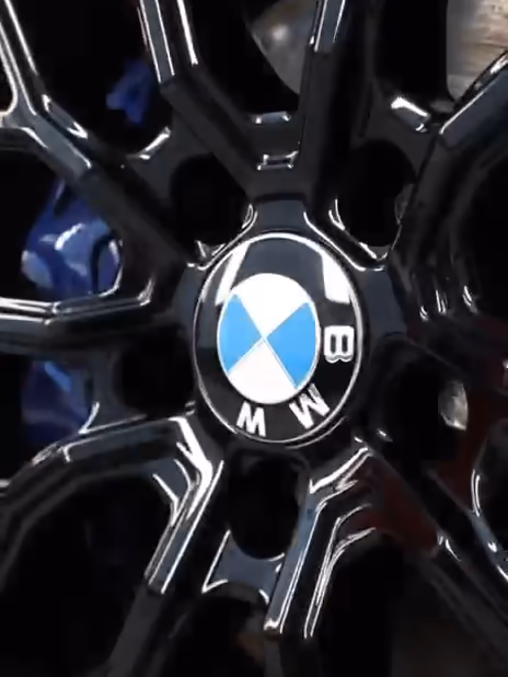 Kiiltävä musta BMW-vanne ja sininen jarrusatula lähikuvassa