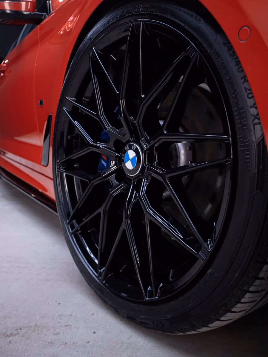 Punaisen BMW:n kiiltävä musta vanne ja rengas lähikuvassa